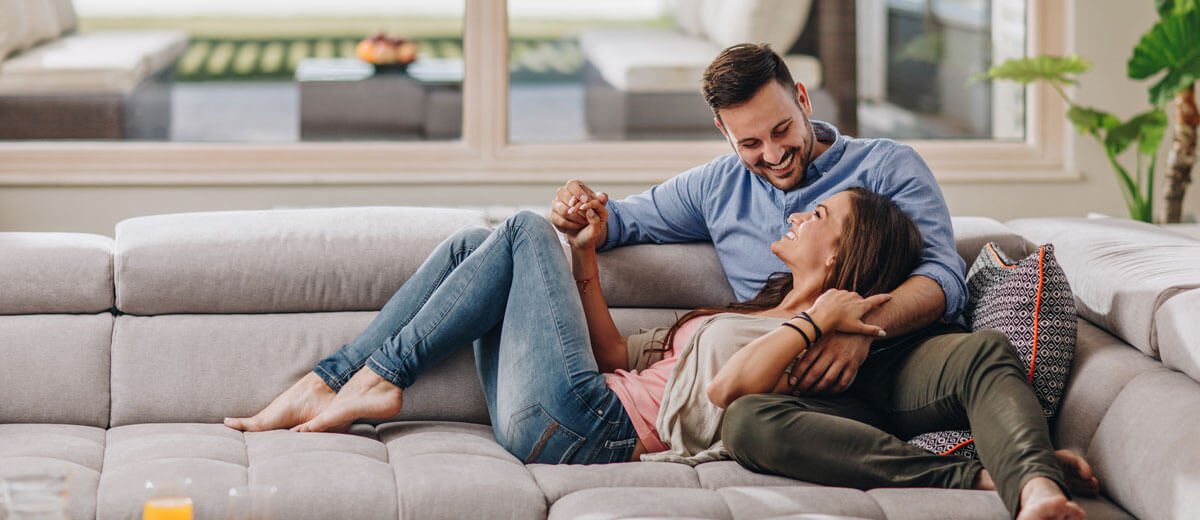 Zwei Personen liegen auf einem grauen Sofa