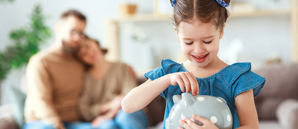 Mädchen steckt Geld in Sparschwein